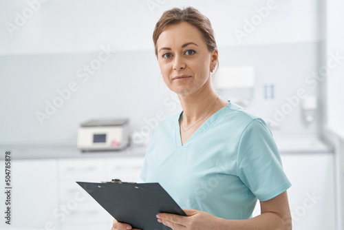 Woman cosmetologist with clipboard standing in beauty salon