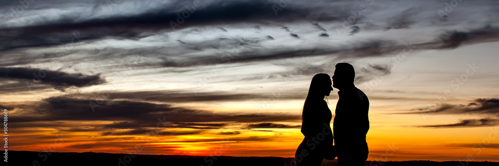 Fototapeta premium Silhouette of couple in love at sunset outdoor format.