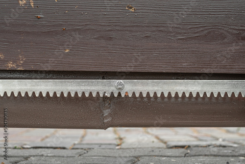 Metal gate rack toothed rail on wooden gate, close up. photo