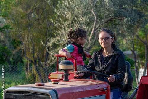 Contrasted view of mother and daughter traveling with tractor with selective focus.