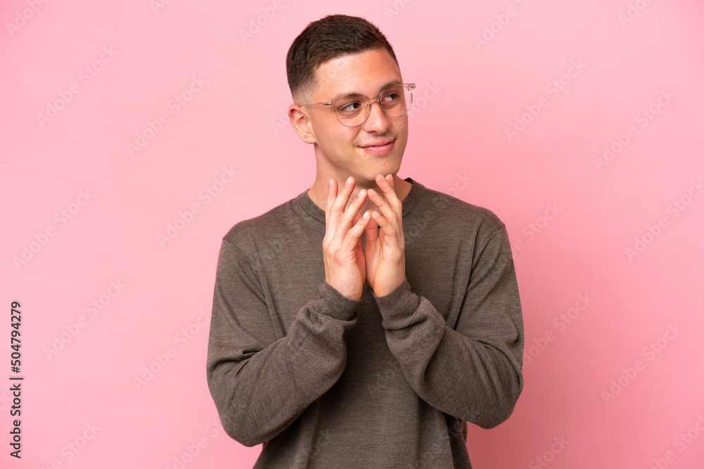 Young Brazilian man isolated on pink background scheming something Young Brazilian man isolated on pink background scheming something