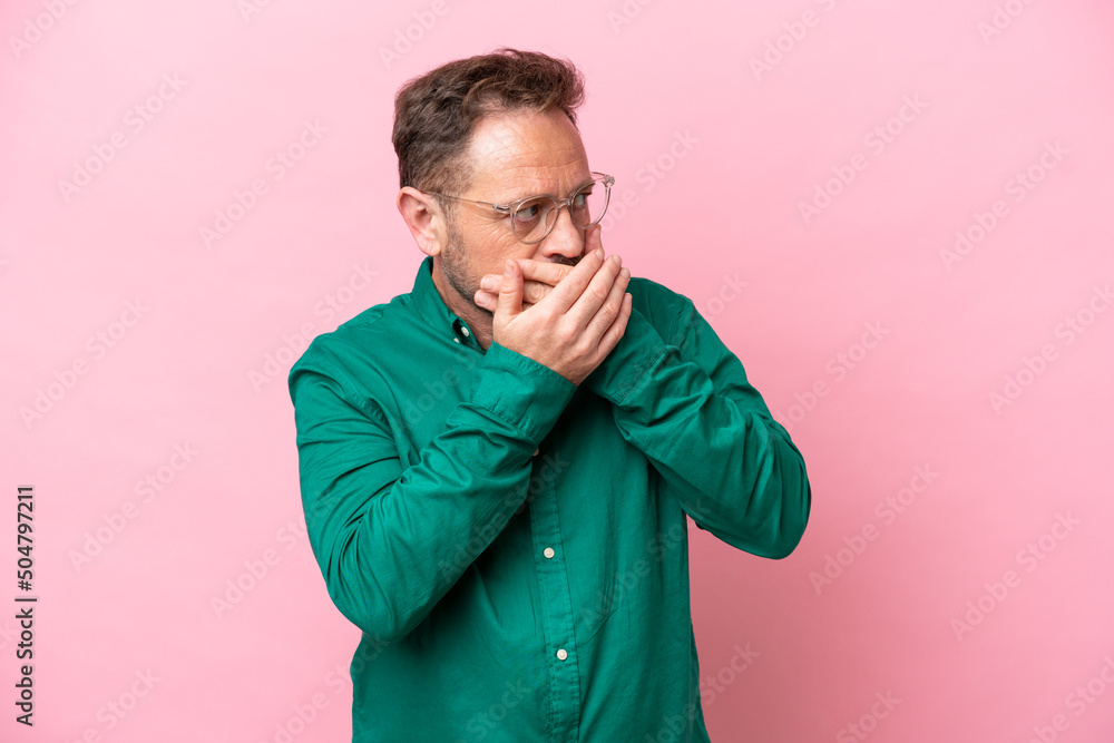 Middle age caucasian man isolated on pink background covering mouth and looking to the side Middle age caucasian man isolated on pink background covering mouth and looking to the side