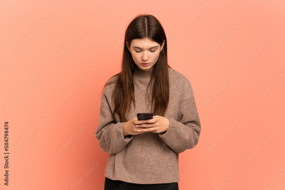 Young Ukrainian girl isolated on pink background using mobile phone Young Ukrainian girl isolated on pink background using mobile phone