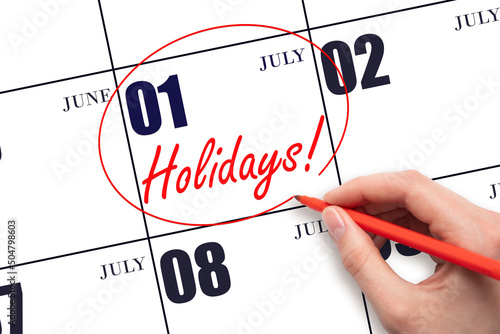 Hand drawing a red circle and writing the text Holidays on the calendar date 1July. Important date. photo