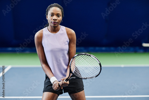 Front view portrait of young black sportswoman playing tennis at indoor court, copy space
