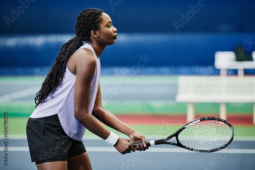 Side view portrait of young black sportswoman playing tennis at indoor court, copy space © Seventyfour