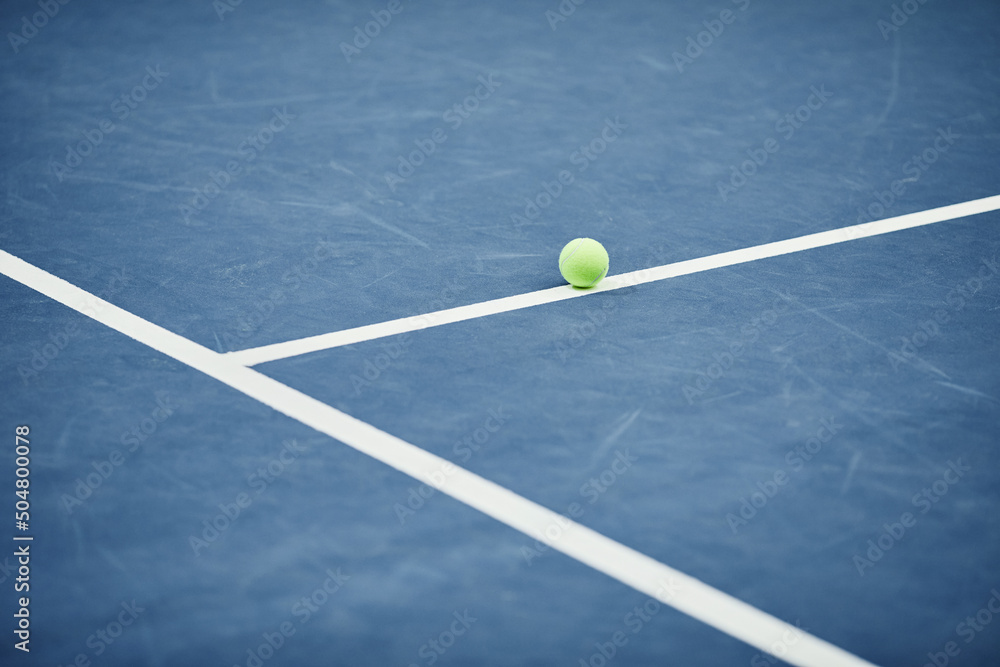 Minimal background image of single yellow tennis ball on blue flooring at tennis court, copy space