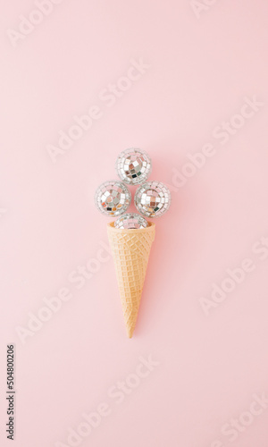 Ice cream cone with four shiny disco balls on pink background. Flat lay. Minimal concept.