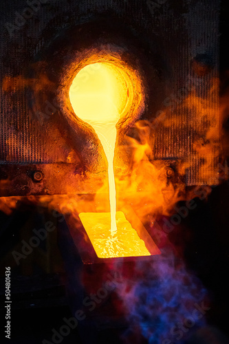 Filling casting form with melted gold in shielding gases photo