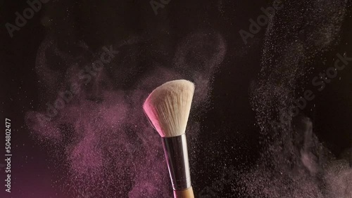 Close up selective focus shot of shimmer powder being shaken off makeup brush photo