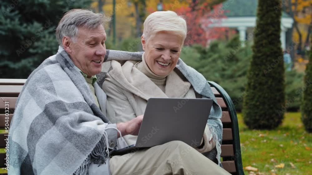 Older happy caucasian husband wife mature elderly couple grandparents family look at screen laptop work remotely browser good news watch funny video on internet choose make online purchases shopping Older happy caucasian husband wife mature elderly couple grandparents family look at screen laptop work remotely browser good news watch funny video on internet choose make online purchases shopping