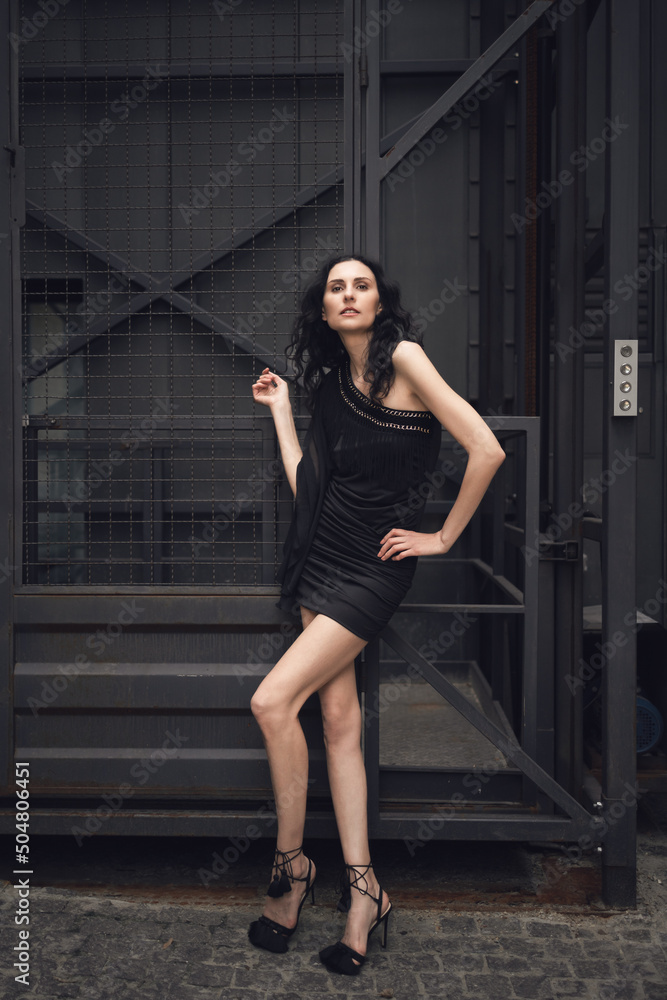 A brunette girl with long legs stands near a freight elevator