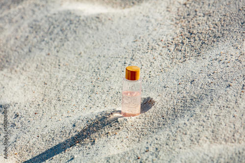 cosmetic bottle in white sand in desert