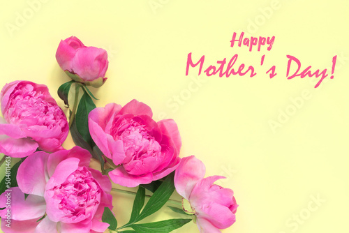 Beautiful bouquet of flowers of delicate peony,  on yellow background. Inscription Happy Mother's Day! Minimal concept backdrop.