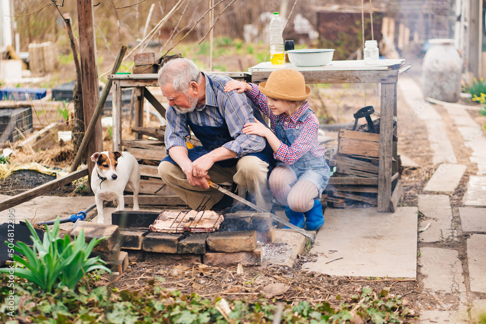 granddaughter helps grandfather with dog cook barbecue on the grill, bonfire granddaughter helps grandfather with dog cook barbecue on the grill, bonfire