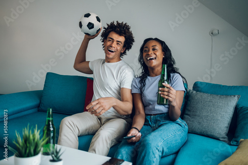 Canvastavla African american couple drinking beer and watching the football game at home