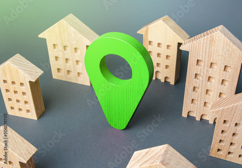Green location indicator among houses. Delivery. Tracking and navigation. Internet of things, city management and city services municipal. Business advertising. Modern eco living housing.