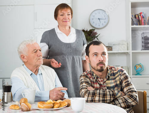 Elderly grandfather teaches his grandson in presence of grandmother photo