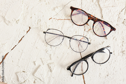 three stylish modern eye glasses on cracked background