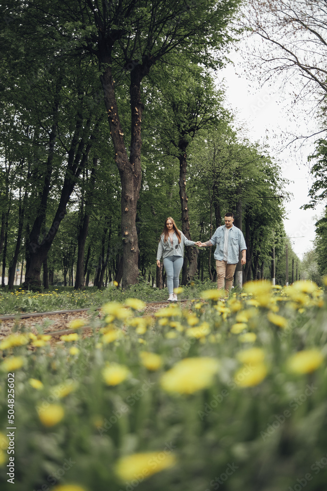 Fototapeta premium a couple in love walks in the park. on the front lan dandelions