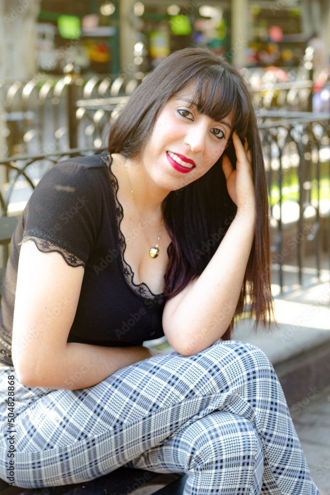 Mexican womansmiling sitting on bench in park with red lipstick Mexican womansmiling sitting on bench in park with red lipstick
