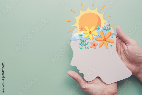 Hands holding paper brain with flowers and sunshine, positive mental health, mindfulness, wellness, self care concept