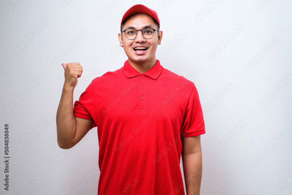 Delivery man with a big smile on face, pointing with hand and finger to the side looking at the camera. Delivery man with a big smile on face, pointing with hand and finger to the side looking at the camera.