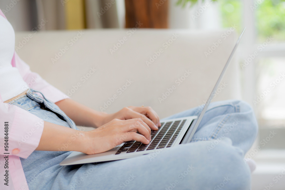 Naklejka premium Closeup hands business woman work from home with laptop computer online to internet on sofa in living room, freelance girl using notebook sitting on couch with comfort and relax, lifestyles concept.