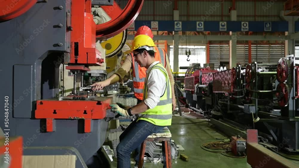 Two young engineers Testing and verifying the operation of the machines forming metal sheet tiles in the factory Two young engineers Testing and verifying the operation of the machines forming metal sheet tiles in the factory