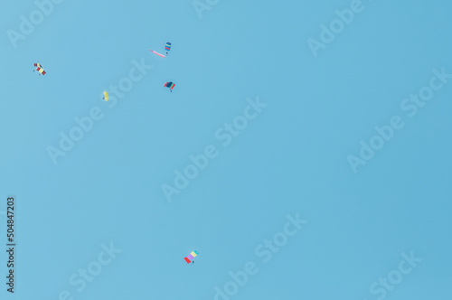 A group of parachutists in a clear sky with colored bright parachutes. Military parade on Victory Day. Copy space.