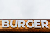Burger restaurant logo, burger word sign in white letters, text written on a tree background, street restaurant, meat food, street food
