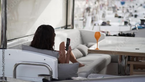A girl rests on a luxury yacht with a phone in her hands. 