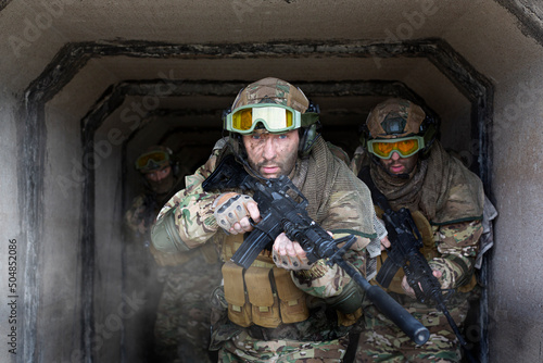 Three military mercenaries walk against the background of a concrete wall and smoke. Photo with copy space. Collage - one model in three poses. photo