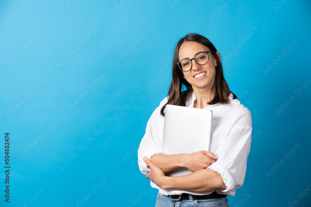 Pretty hispanic woman holding laptop and looking at camera isolated on blue background. Happy businesswoman smiling Pretty hispanic woman holding laptop and looking at camera isolated on blue background. Happy businesswoman smiling