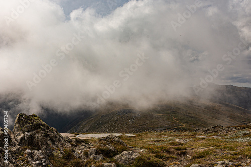 Fog hovering over alpine mountain ranges on winters day. Misty cloud covering mountain valley from summit