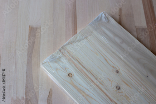 Furniture board in cellophane packaging on a wooden background. Wooden plank.