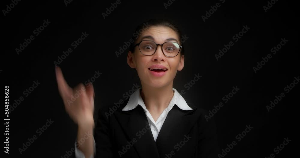 Beautiful businesswoman with glasses with her hair gathered in a bun, dressed in office clothes, thinking about something,holding her index finger near her lips, remembering.Isolated black background Beautiful businesswoman with glasses with her hair gathered in a bun, dressed in office clothes, thinking about something,holding her index finger near her lips, remembering.Isolated black background