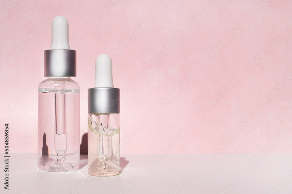Dropper bottles with cosmetic oil on a pink background. Side view, space for text. Dropper bottles with cosmetic oil on a pink background. Side view, space for text.