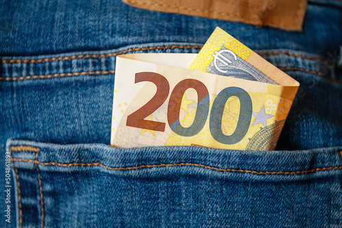 A 200 Euro banknote with the Euro symbol in the pocket of a pair of jeans. Concept about savings, wealth, profits, investments or the use of cash. photo