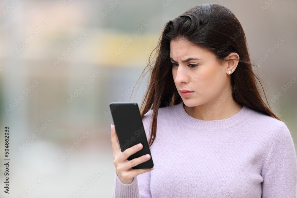 Worried woman reads phone content in the street Worried woman reads phone content in the street