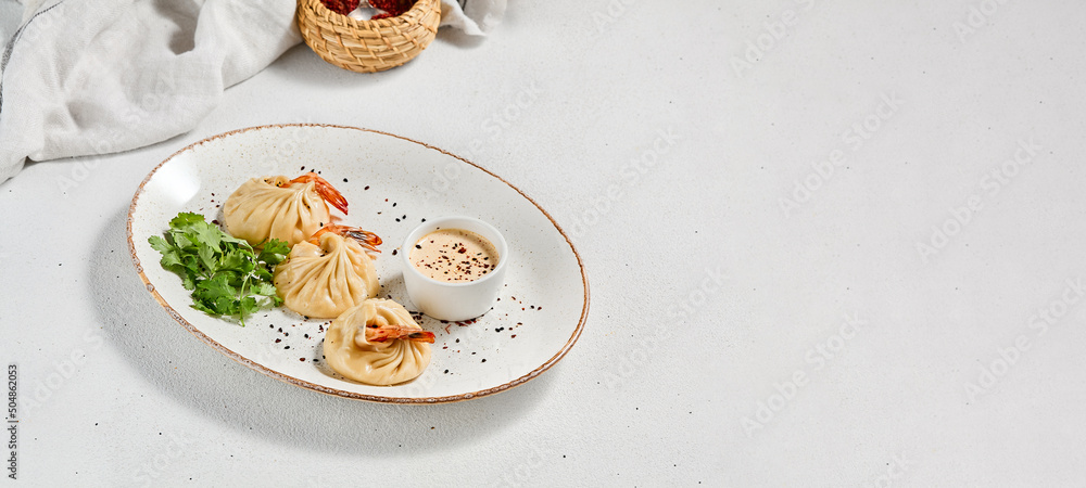 Steamed dumplings shrimp in asian style on white concrete background. Prawn dim sum with sauce on ceramic plate. Shrimp wontons on dish in minimal style. Asian dumplings with seafood. Steamed dumplings shrimp in asian style on white concrete background. Prawn dim sum with sauce on ceramic plate. Shrimp wontons on dish in minimal style. Asian dumplings with seafood.