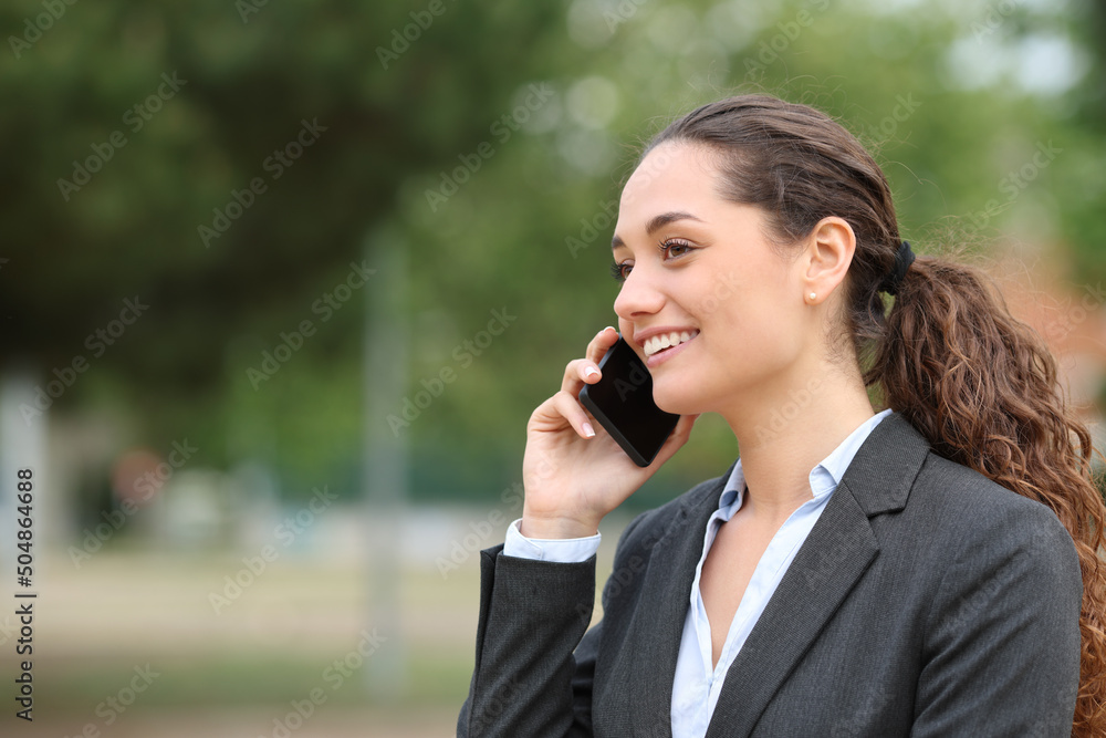 Happy businesswoman talking on cell phone in a park Happy businesswoman talking on cell phone in a park