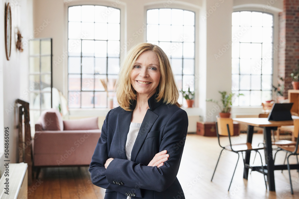 Happy businesswoman with arms crossed standing in living room at home Happy businesswoman with arms crossed standing in living room at home