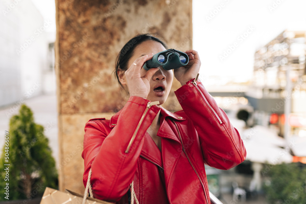 Shocked young woman with mouth open looking through binoculars Shocked young woman with mouth open looking through binoculars