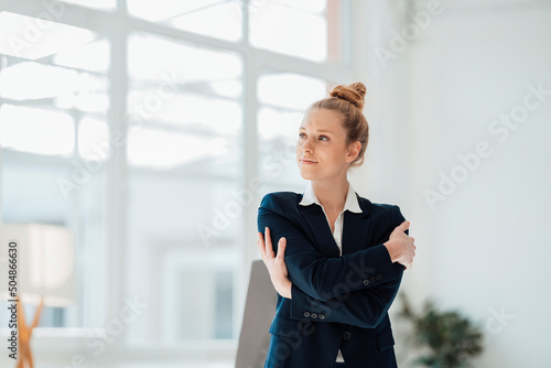 Contemplating businesswoman hugging self at office photo