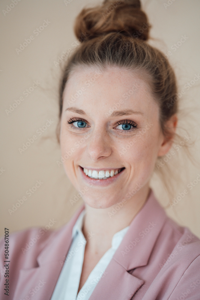 Young happy businesswoman with hair bun by wall Young happy businesswoman with hair bun by wall