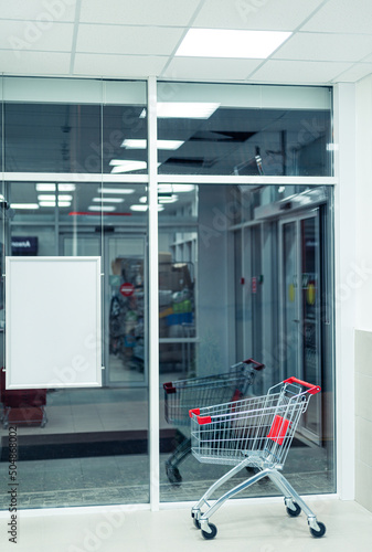 lone shopping cart in supermarket entrance hall with empty banner photo