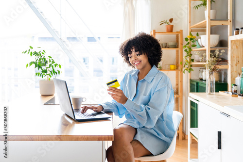 Happy woman making payment through credit card on laptop photo