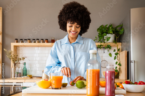 Beautiful woman cutting fruit with knife on board in kitchen at home photo