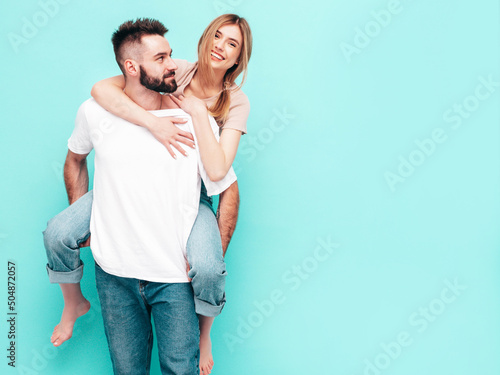 Sexy smiling beautiful woman and her handsome boyfriend. Happy cheerful family having tender moments near blue wall in studio.Pure cheerful models hugging.Gives piggyback riding